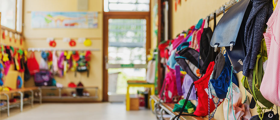 Empty hallway in the school, backpacks and bags on hooks, bright recreation room